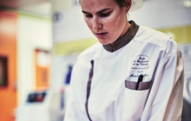 Une femme concentrée portant une blouse blanche de chef une cuisine